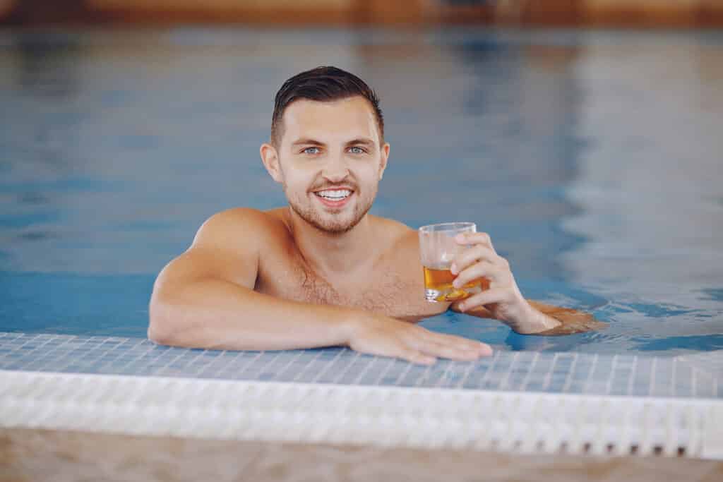 Homem tomando whisky na piscina